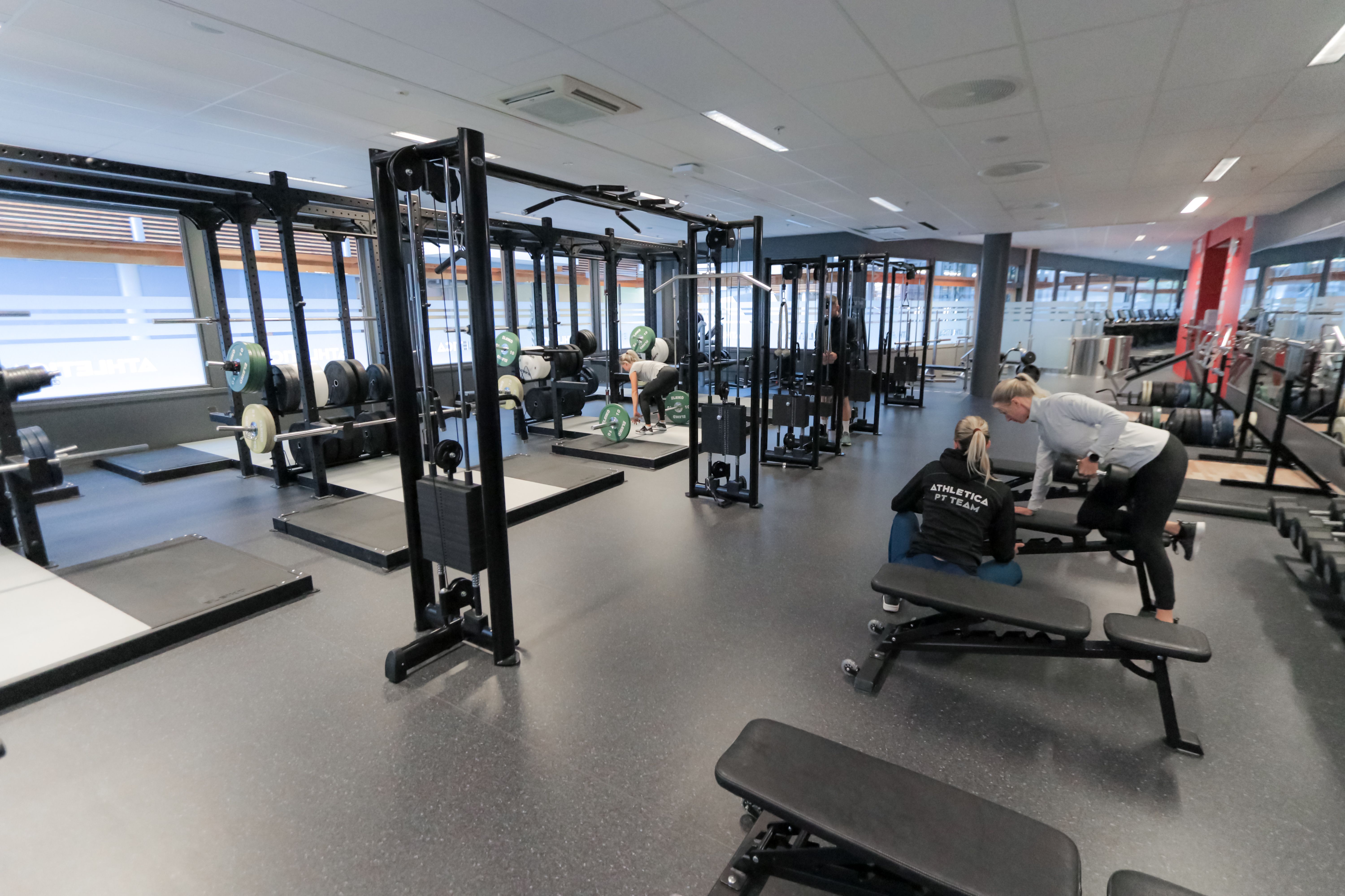 Foto av studenter som trener styrke i treningshall på AiO Athletica senter Nydalen.