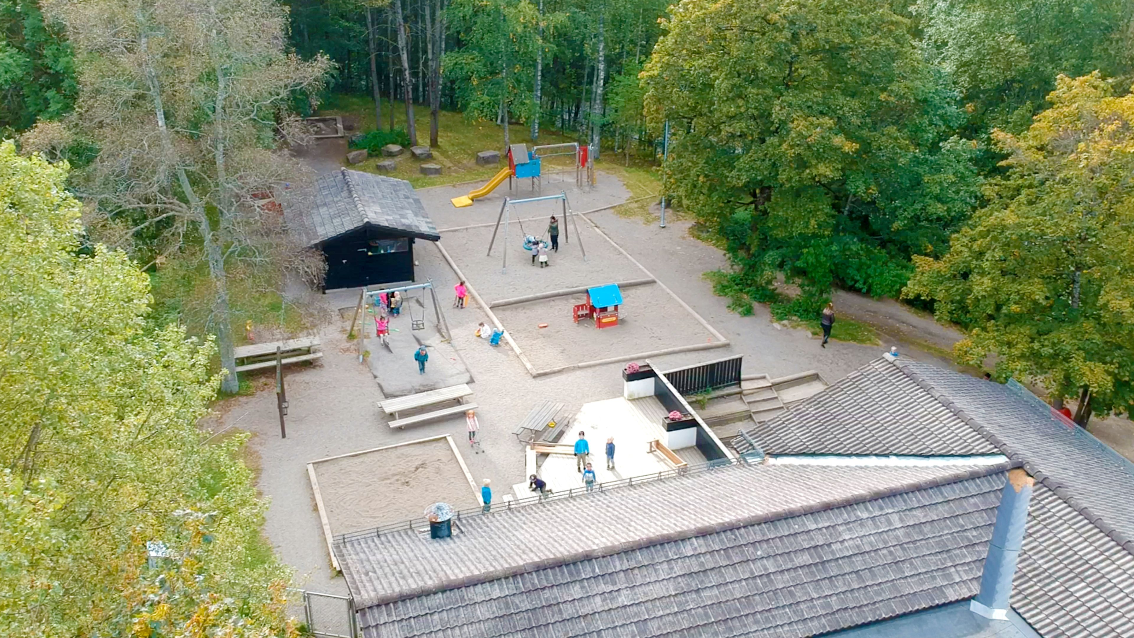 Oversiktsbilde av lekeområder ute på Frydenhaug. Mange barn som leker