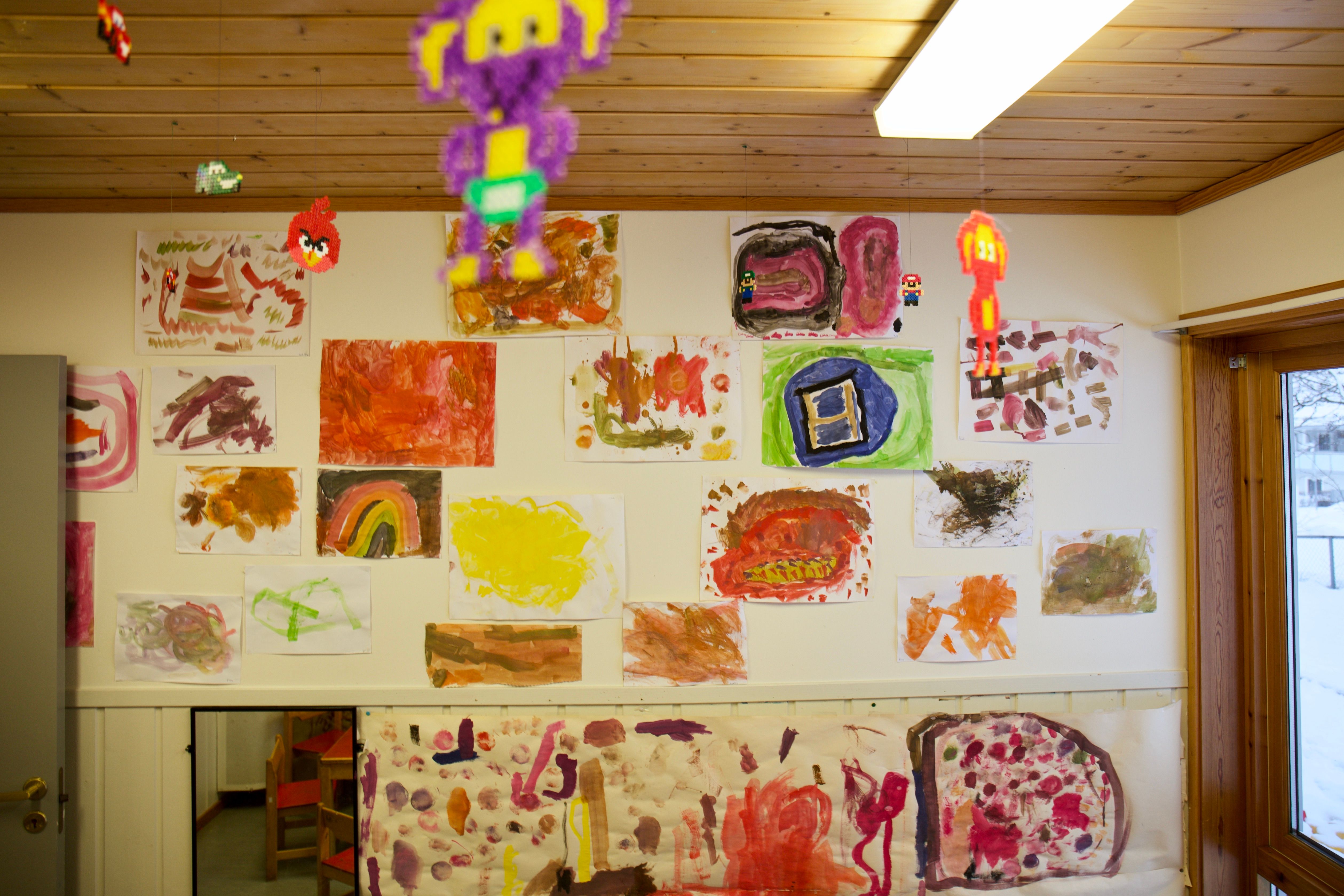 Mange fargerike barnetegninger på en vegg