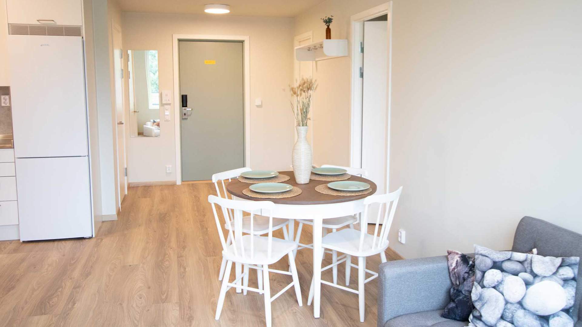 Foto av kjøkkenkrok, sofa og inngangsdør.