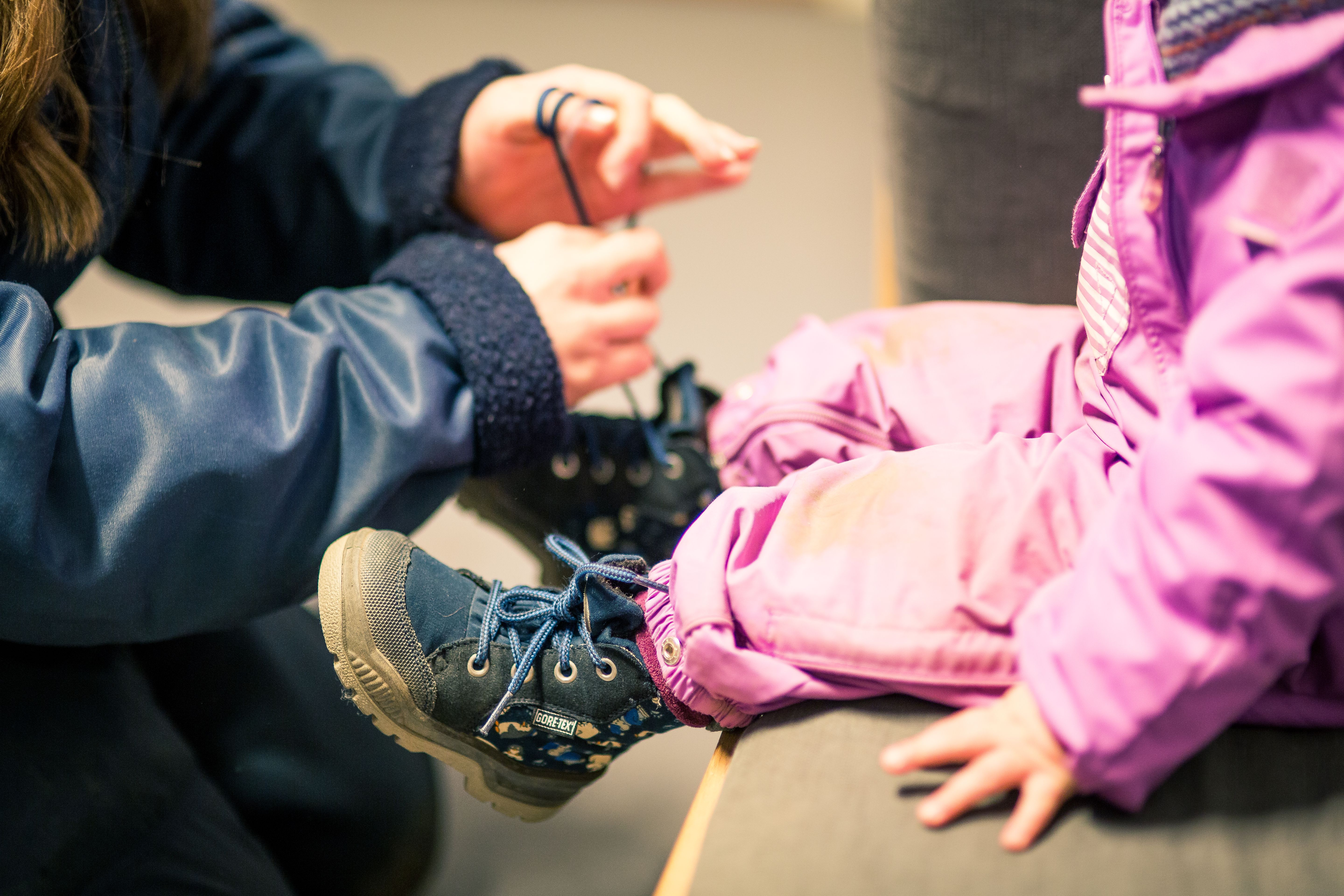 En voksen som knyter skoene til et barn