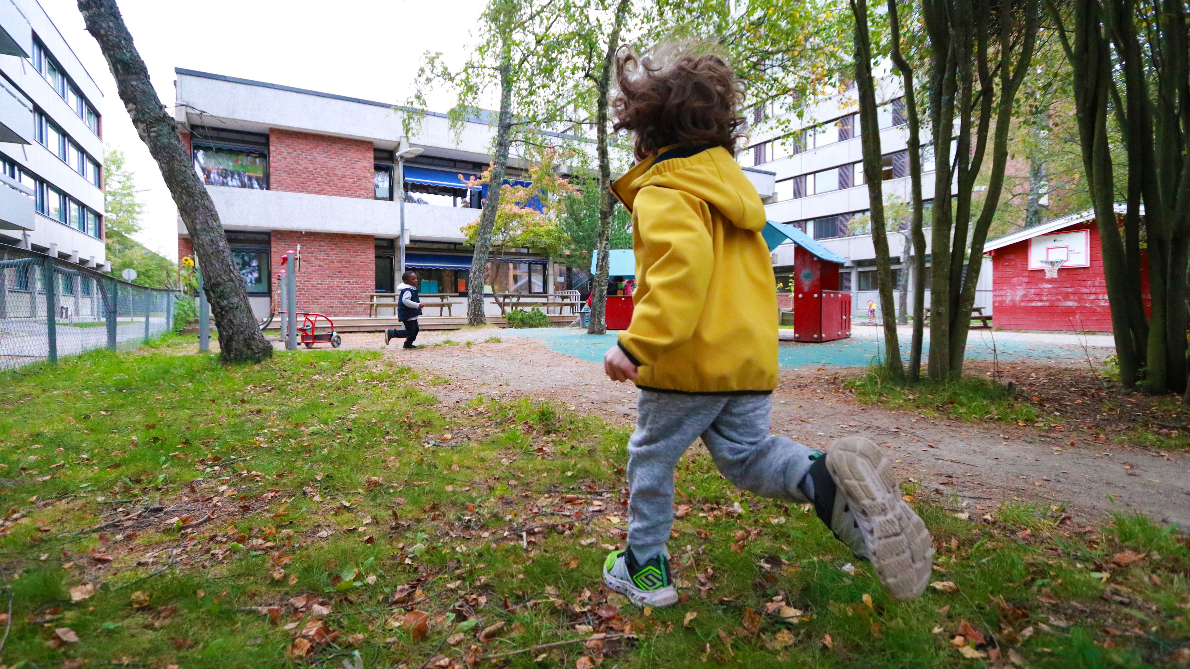 Barn i gul jakke som løper mot Klossen SiO Barnehage