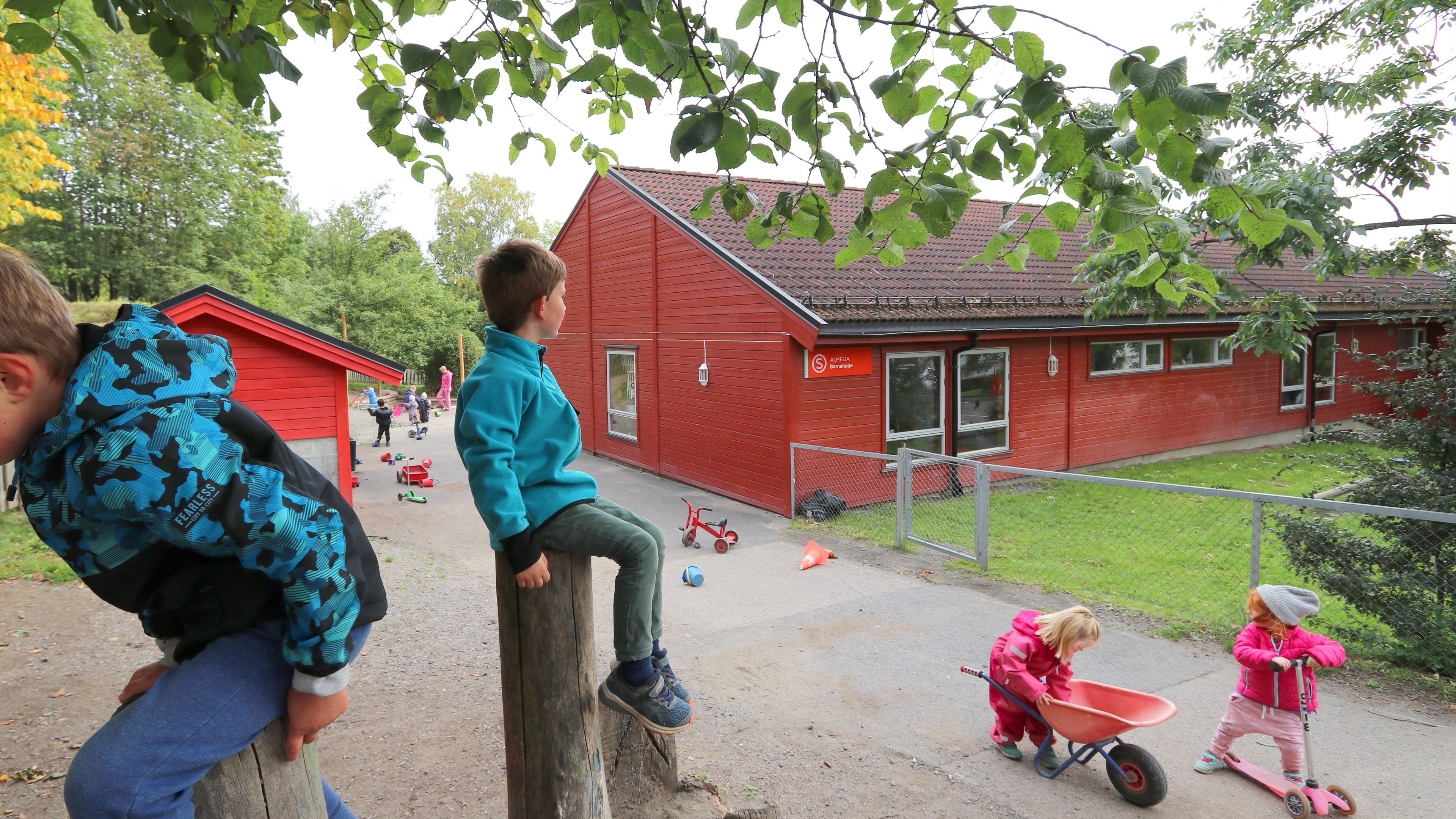En gutt på en stolpe som ser på andre barn på en lekeplass